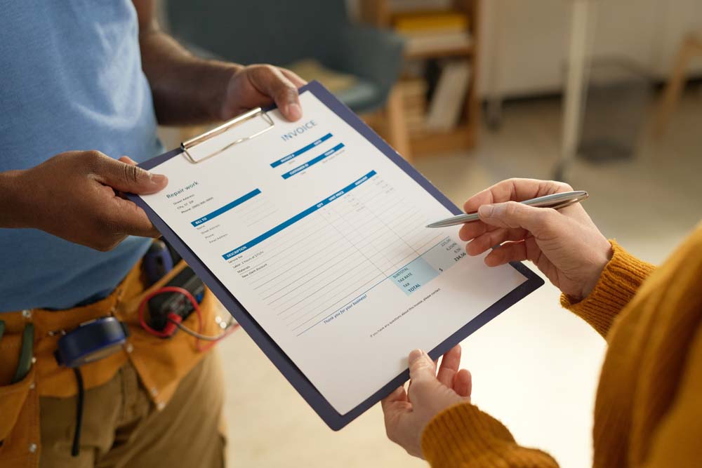 a plumber holding a clipboard saying “Invoice”